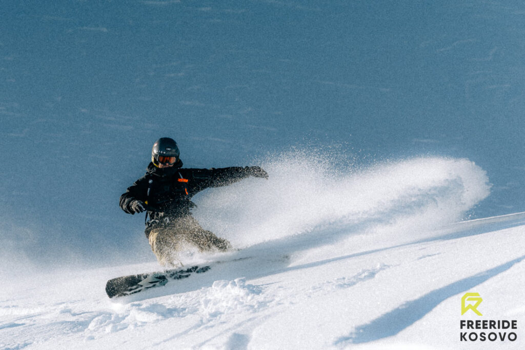 Snowboarder carving through deep powder