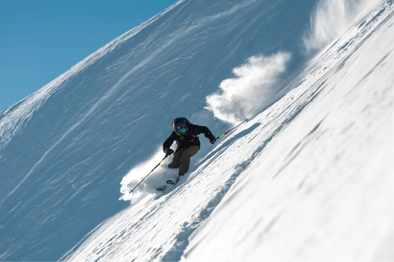 Snowboarder carving through deep powder in the Accursed Mountains